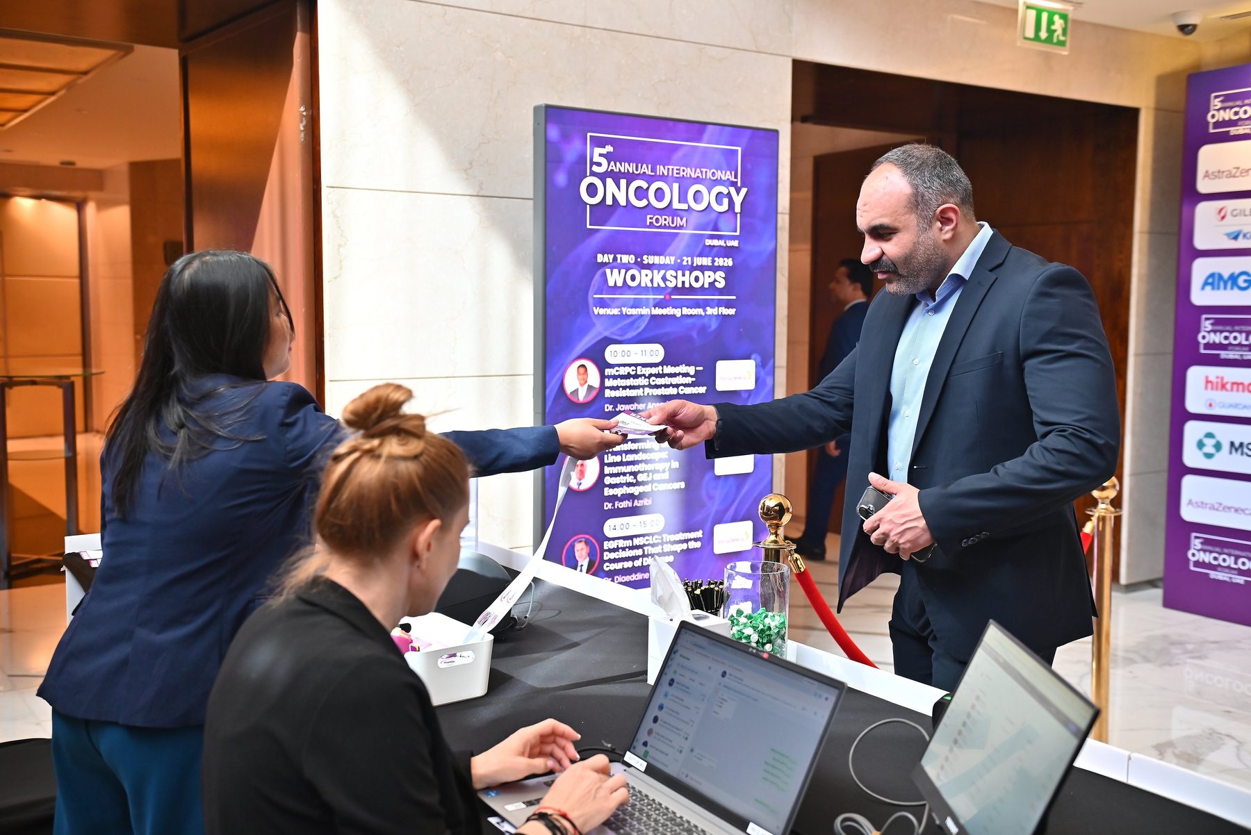 Pixanova portable LED roll-up screen displaying the day's workshop schedule beside the registration desk at the International Oncology Forum 2026, Shangri-La Dubai
